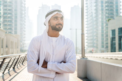 Young man looking away while standing in city