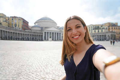 Girl taking selfie photo in naples with piazza del plebiscito square on the background naples, italy