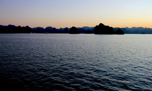 View of calm sea with silhouette mountain in background