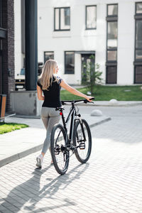 Rear view of woman riding bicycle on street in city