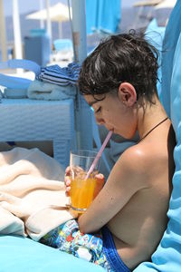 Boy drinking water from while sitting on bed