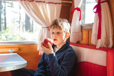 Boy eating apples while sitting in vehicle trailer