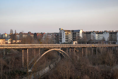 Bridge over river by buildings against sky in city