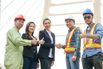 Portrait of business people with engineers standing against bridge