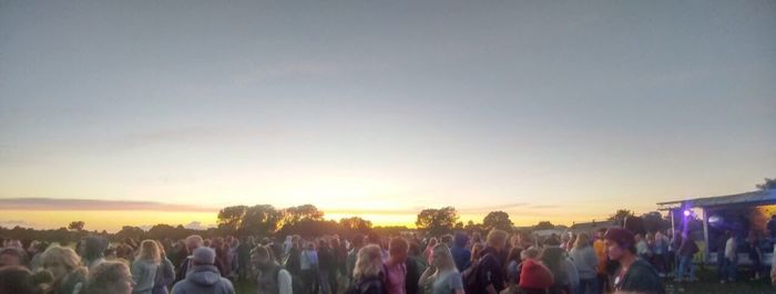 Crowd at music concert against sky during sunset