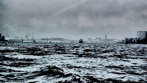 Boats in sea against cloudy sky