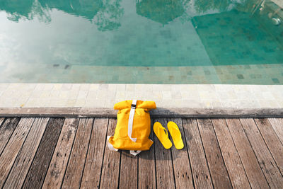High angle view of yellow container on wooden table by swimming pool