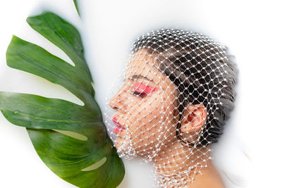 Young woman with face covered by net taking milk bath