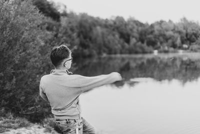 Rear view of man standing by lake