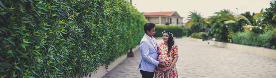 Portrait of pregnant woman with man standing on footpath 