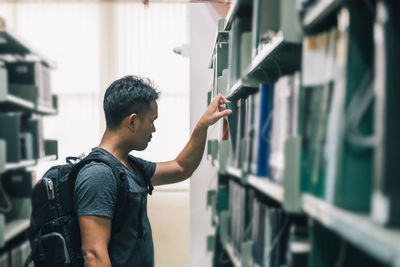 Side view of young man reading book