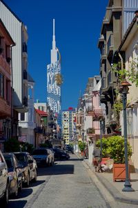 Cars on road by buildings against clear blue sky