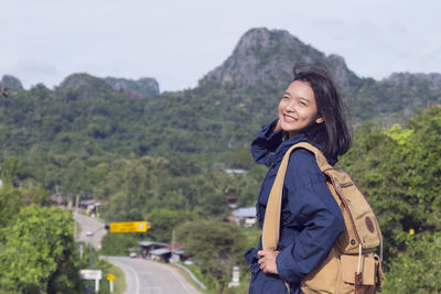 Portrait of smiling young woman standing on landscape