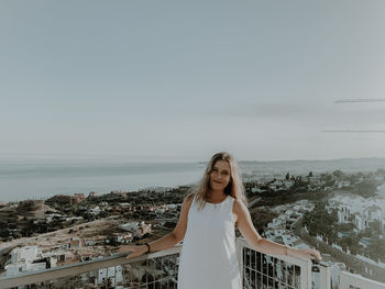 Young woman standing by sea against sky