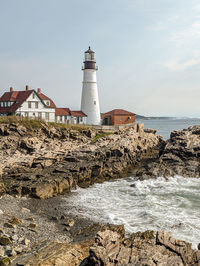 Lighthouse by sea against sky