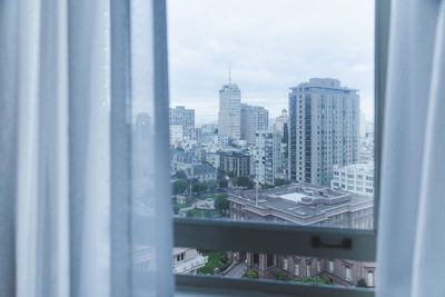 Cityscape against sky seen through glass window