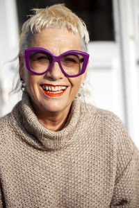 Portrait of amused fashionable senior woman with cool haircut and large purple eyeglasses