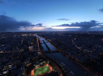 High angle view of illuminated city by river against sky