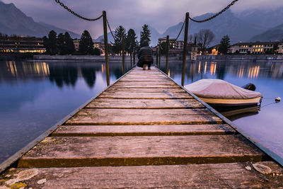 Pier over lake against sky at dusk