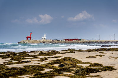 Lighthouse by sea against sky
