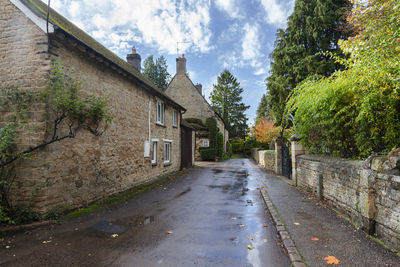 Footpath amidst houses against sky