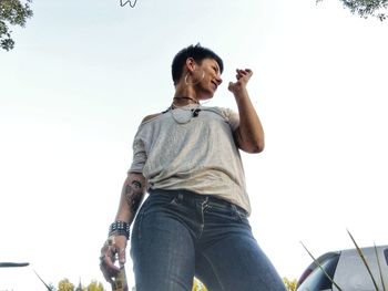 Low angle view of young man looking away against sky