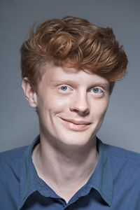 Portrait of young man against grey background, smiling