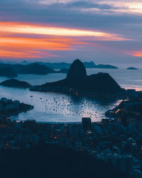 Scenic view of sea by buildings against sky during sunset