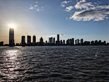 Sea by modern buildings in city against sky