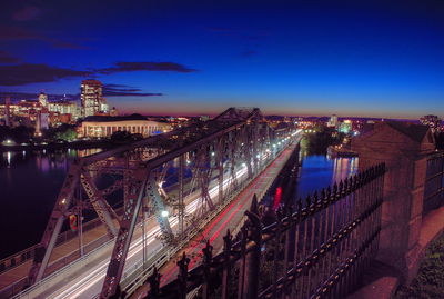 Illuminated bridge over river against sky at night