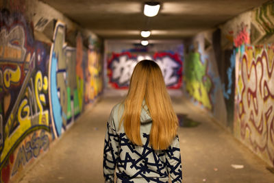 Rear view of woman standing against graffiti