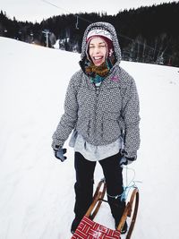 Portrait of young woman standing on snow covered field