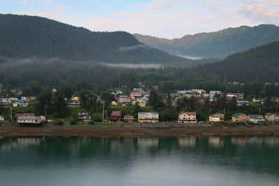 Scenic view of townscape by mountains against sky