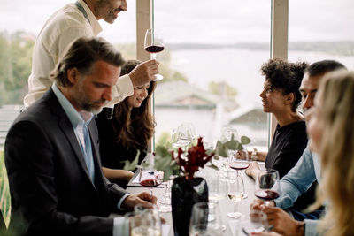 Male and female coworkers with red wine at table during kick off meeting in convention center