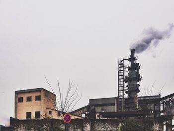 Smoke emitting from factory against clear sky