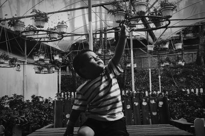 Cute boy reaching towards potted plants in garden