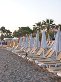 Lounge chairs on beach against clear sky