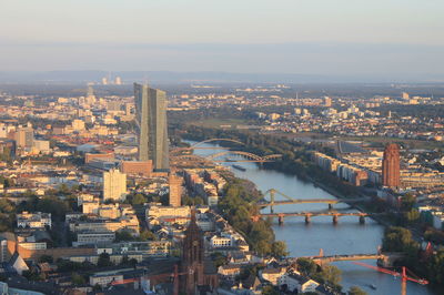 Aerial view of bridge over river in city against sky