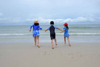 Rear view of women on beach against sky