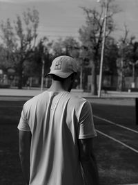 Rear view of man wearing hat standing against trees