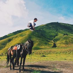 Side view of man jumping in mid air against green mountains