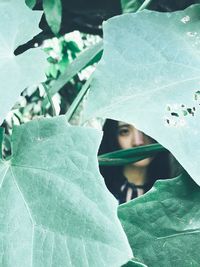 Close-up of young woman with green leaves