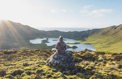 Young woman sitting on rock at corvo island, azores, portugal