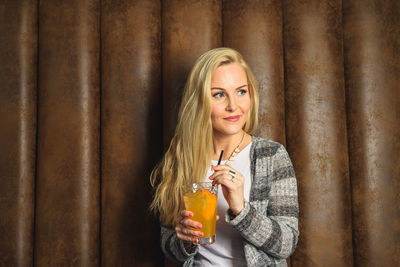 Adult woman with cocktail near leather wall