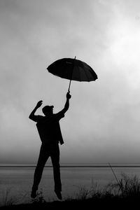 Full length of silhouette man standing in water against sky