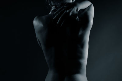 Rear view of shirtless woman against black background