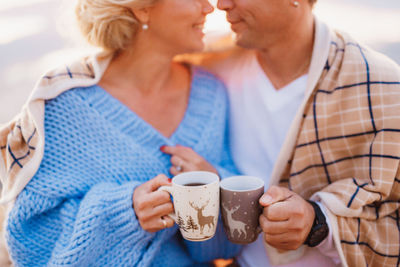 Midsection of couple holding coffee cup