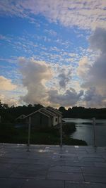 Houses by lake against sky during sunset