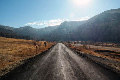 Road leading towards mountains against sky