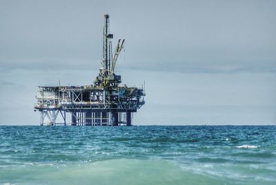 Oil rig in sea against sky